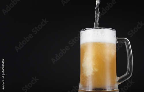 Glass of beer with foam on a dark background