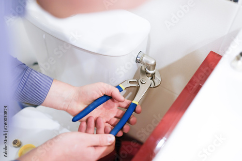 Sanitary worker performs repair of toilet bowl. To repair the pipe from the toilet