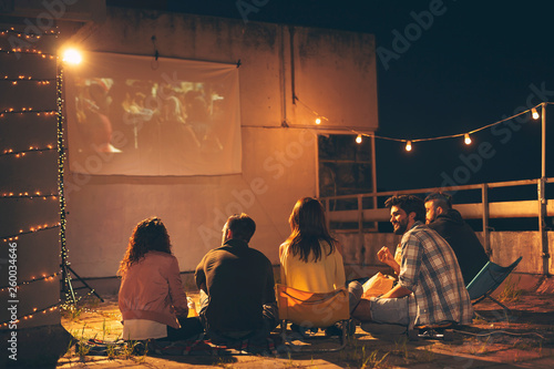 Friends watching a movie on a building rooftop terrace
