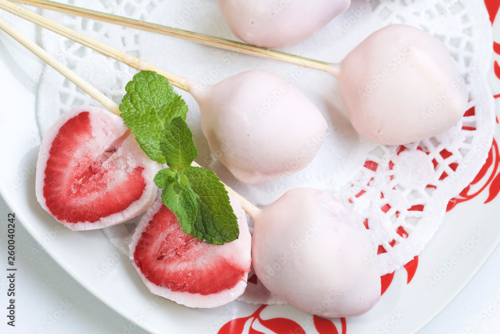 Strawberries in yogurt. Berries are dressed on wooden skewers and dipped in yogurt. Nearby are two halves of dessert. Visible red juicy strawberry flesh. Decorated with mint leaves. Strawberries in yogurt. Berries are dressed on wooden skewers and dipped in yogurt. Nearby are two halves of dessert. Visible red juicy strawberry flesh. Decorated with mint leaves.