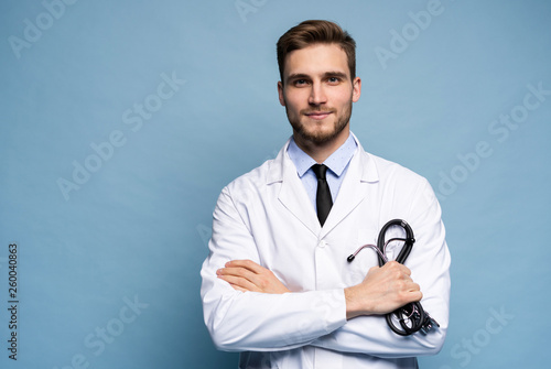 Portrait of confident young medical doctor on blue background. photo