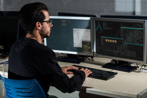 Young computer science student developing with his computer on a Linux System over double screen system photo