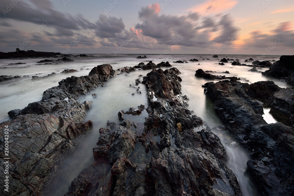 Long exposure seascape over the rocky beach during sunrise in Terengganu, Malaysia. Nature background.