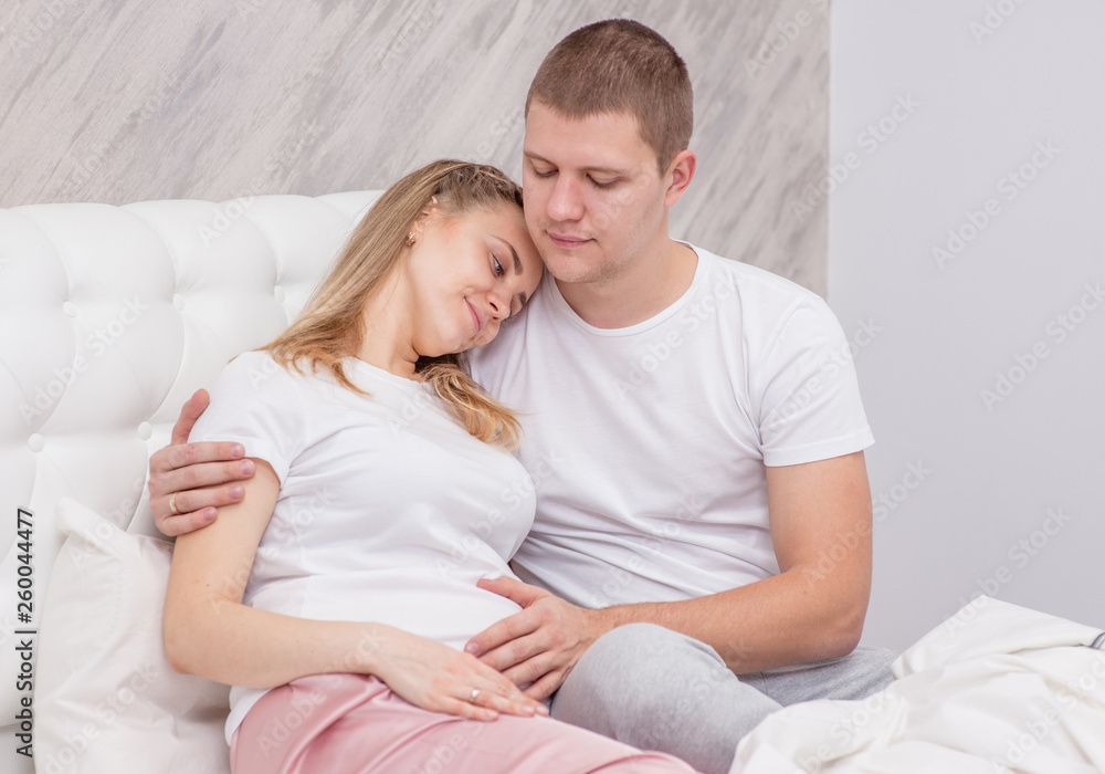 Young man hugging his sad pregnant wife on the bed at home Young man hugging his sad pregnant wife on the bed at home