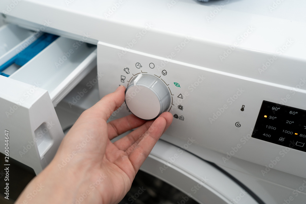 Close-up. Female chooses the fast mode in an automatic washing machine. Side view Close-up. Female chooses the fast mode in an automatic washing machine. Side view
