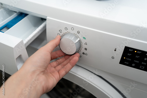 Close-up. Female chooses the eco mode in an automatic washing machine. Side view