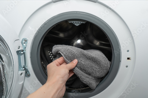 Female hand holds clean gray cotton towel just washed in an automatic washing machine