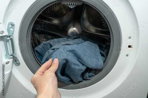 Female hand holding jeans just washed in an automatic washing machine
