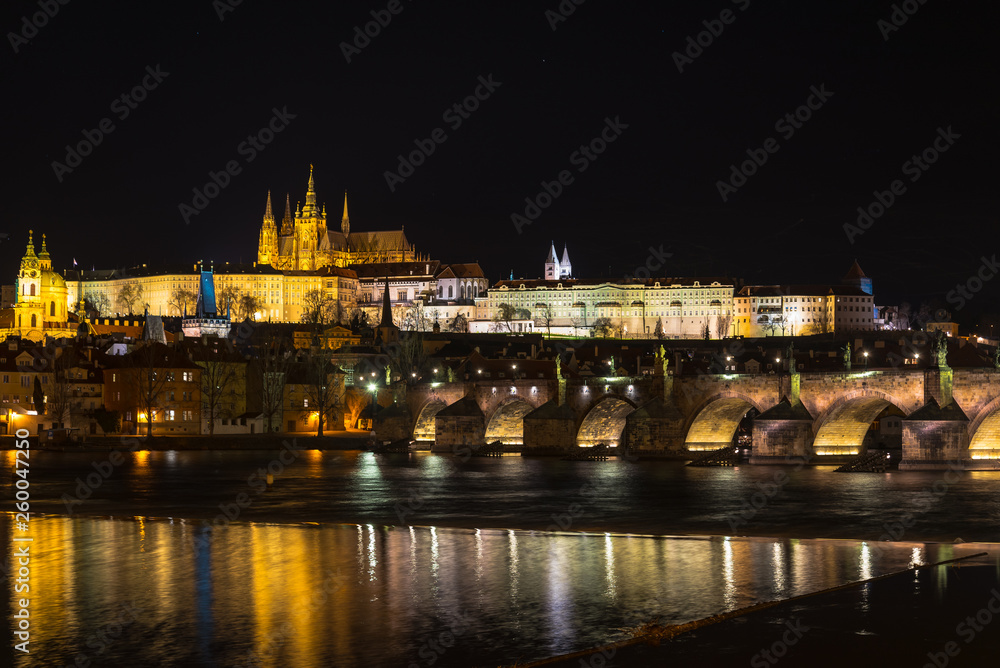 The Prague castle with historic Charles Bridge and Vltava river in the night scene with water reflection. Prague is a popular travel destination. Prague, Czech Republic