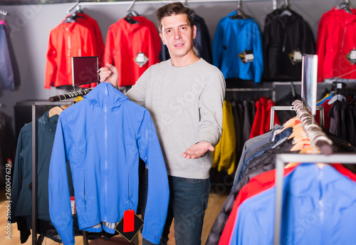 smiling athlete chooses sporty clothes and comfortable shoes in the sports shop