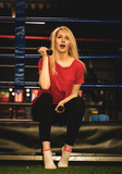 Beautiful sexy woman wearing sportswear seated with dumbbells on the edge of a boxing ring. Boxer girl Femininity and positive in brutal sport concept.