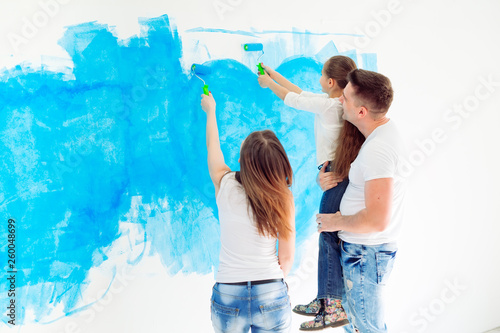 Mother, father and little daughter painting the wall in their new home.