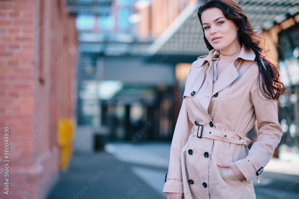 Fototapeta premium Stylish and cheerful. Beautiful young woman looking at camera with smile while standing outdoors