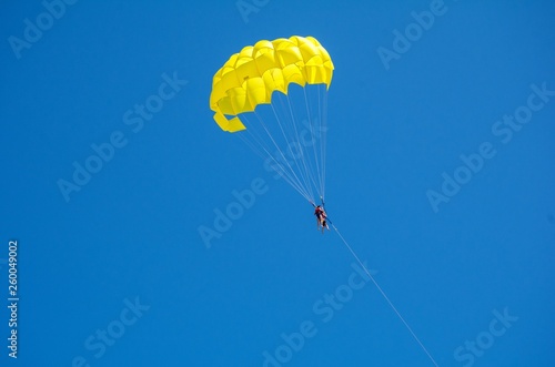 parasailing, yellow parachute in the blue sky, active, extreme rest. Beach entertainment.