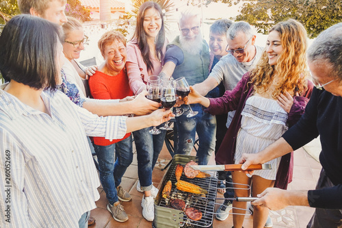 Happy family cheering and toasting with red wine glass at barbecue party - People with different ages having fun drinking and grilling meat at bbq dinner - Friendship, food and weekend activities