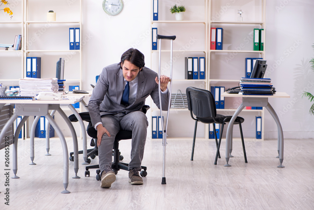 Leg injured male employee working in the office 