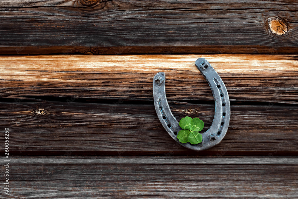 Old horseshoe and four leaf clover on a vintage wooden board. The concept of luck, luck, luck. St. Patricks Day card.