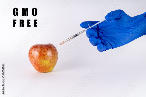Injection of a red apple with a syringe. GMO free. Genetically modified fruit on white background