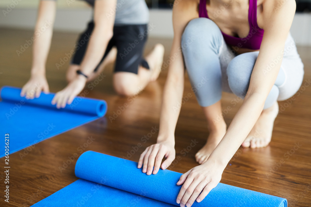 Close-up of unrecognizable yoga students rolling out yoga mats after practice in studio while coming home Close-up of unrecognizable yoga students rolling out yoga mats after practice in studio while coming home