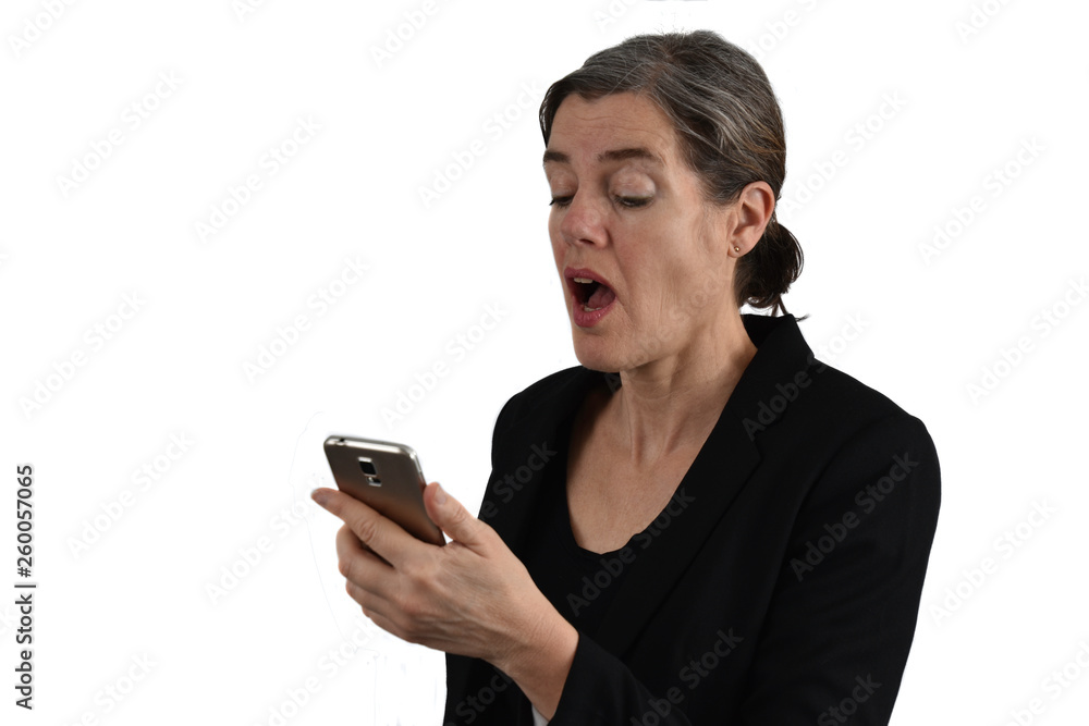 Attractive middle-aged woman with graying hair looks surprised with open mouth on her phone. White background. Attractive middle-aged woman with graying hair looks surprised with open mouth on her phone. White background.