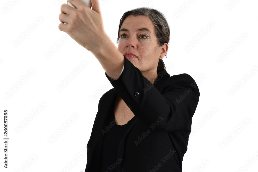 Attractive middle-aged woman with graying hair makes a selfie with her phone. White background. Attractive middle-aged woman with graying hair makes a selfie with her phone. White background.