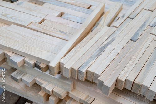 A pile of boards in a carpentry shop. Wood prepared for production in an industrial plant. Light background. photo
