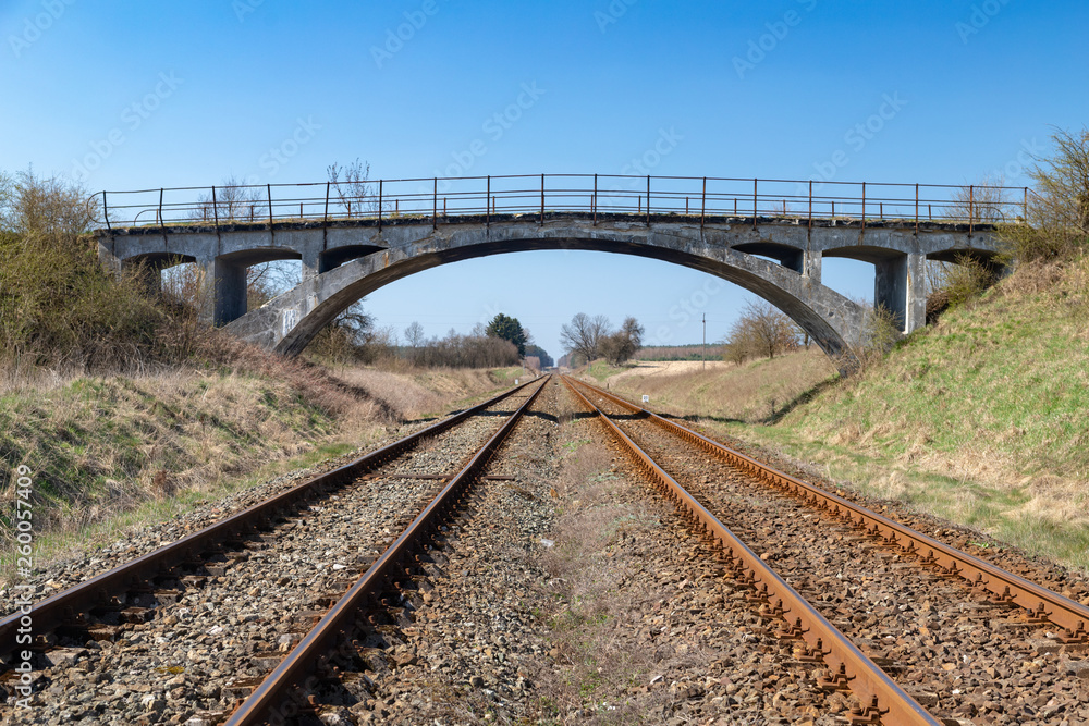 Obraz premium Old viaduct over the railway tracks. Concrete bridge over the railroad.
