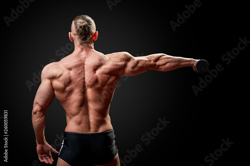 Athletic man posing. Photo of man with perfect physique on black background. Back view. Strength and motivation