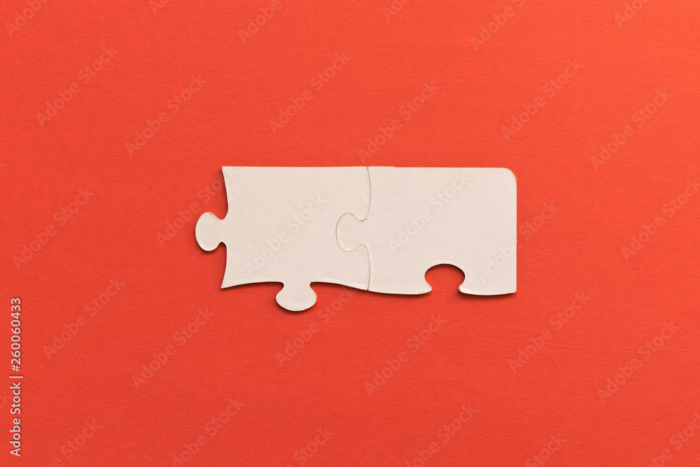 White jigsaw puzzles on red background. The concept of development of thinking. The concept of teamwork. White jigsaw puzzles on red background. The concept of development of thinking. The concept of teamwork.