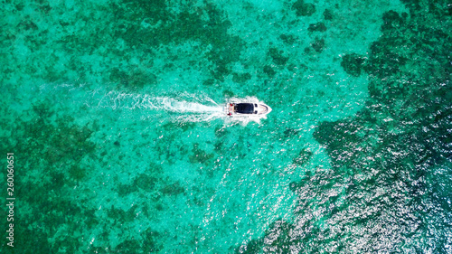 Sports boat in the blue sea. The view from the drone. Expensive vacation. Yacht and turquoise, clear water. Transparent bottom of the water. Visible coral and cliff in the water. Travel to Asia.