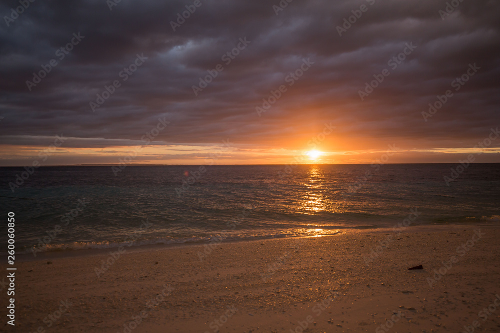 calm sea water beach with white sand, in a tranquil colorful summer sunset dusk background photo