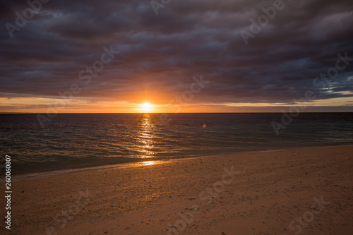 calm sea water beach with white sand, in a tranquil colorful summer sunset dusk background photo