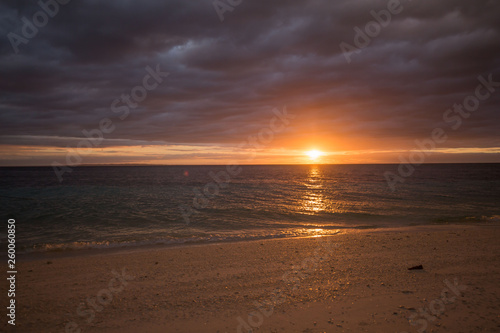 calm sea water beach with white sand  in a tranquil colorful summer sunset dusk background photo