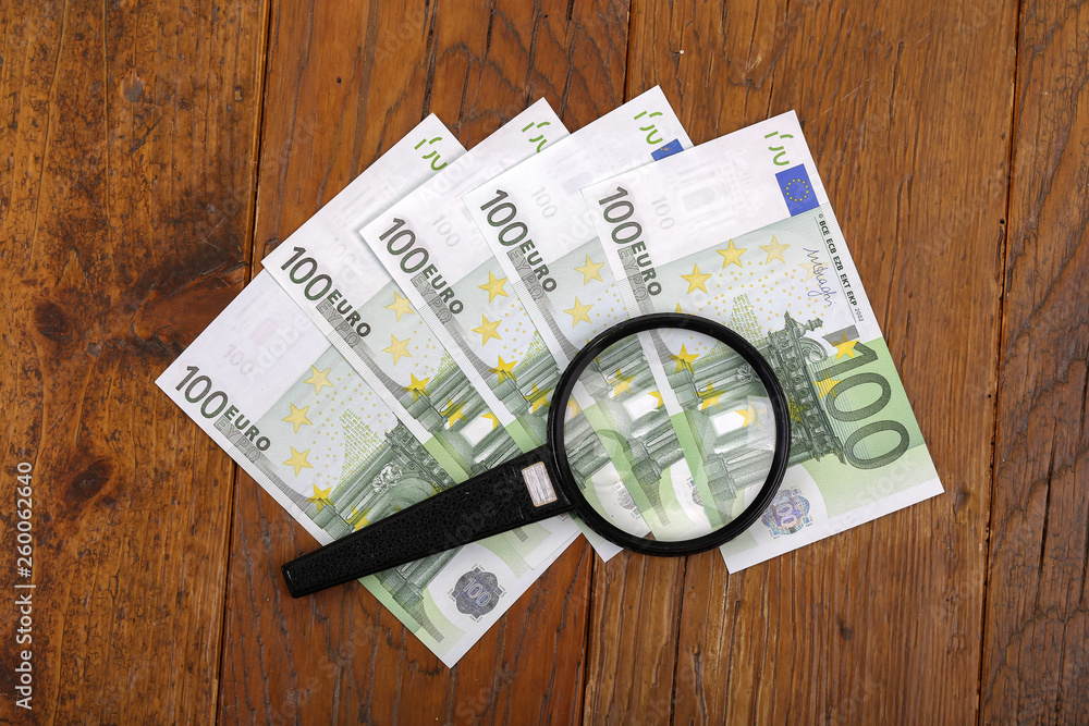 Euro is lying on the table under a magnifying glass. Euro is lying on the table under a magnifying glass.