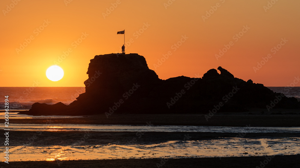Sonnenuntergang am Meer hinter einem Felsen in Cornwall