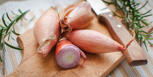 Tableau sur toile Close-up of shallots with fresh rosemary on cutting board
