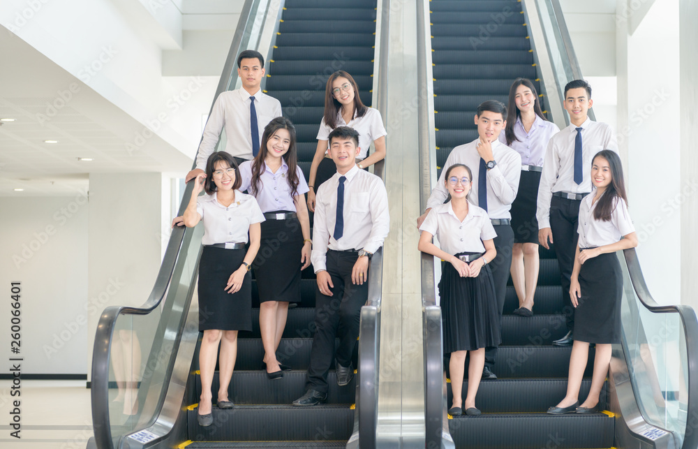 Smart young students standing together on escalator