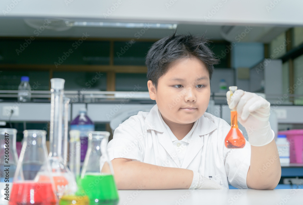 Happy little scientist in lab coat making experiment Happy little scientist in lab coat making experiment