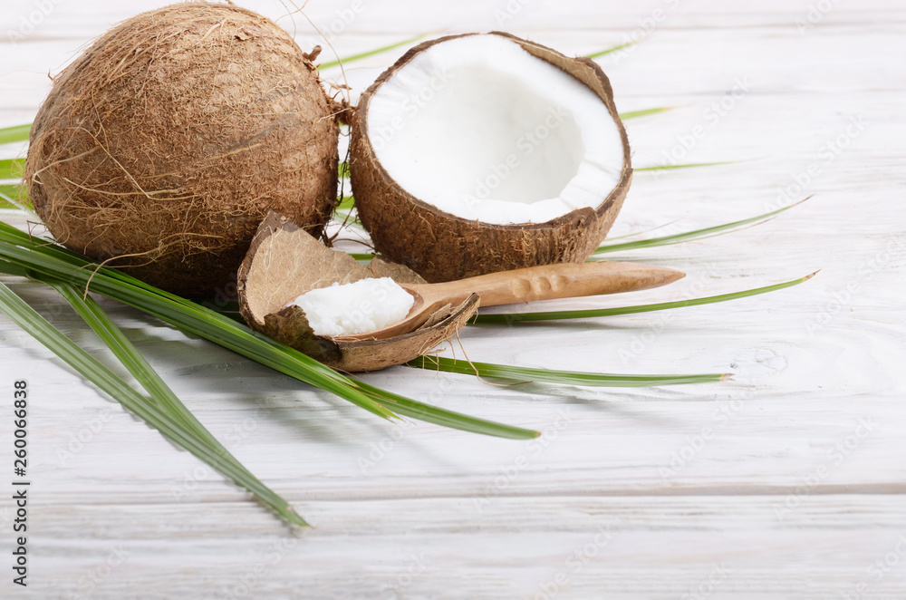 Coconut shell pieces and palm leaves on white wooden table Coconut shell pieces and palm leaves on white wooden table