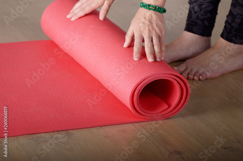 Female hands unrolling yoga mat before workout exercise. Healthy lifestyle concept