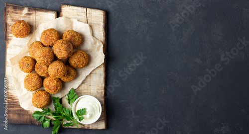 Vegetarian chickpeas falafel balls on wooden rustic board. Traditional Middle Eastern and arabian food. Dark background. Copy space.