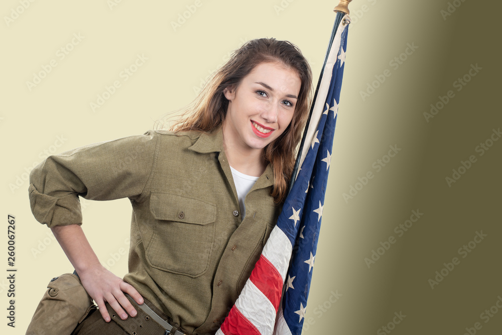 Young woman in US military uniform holding up an American flag.