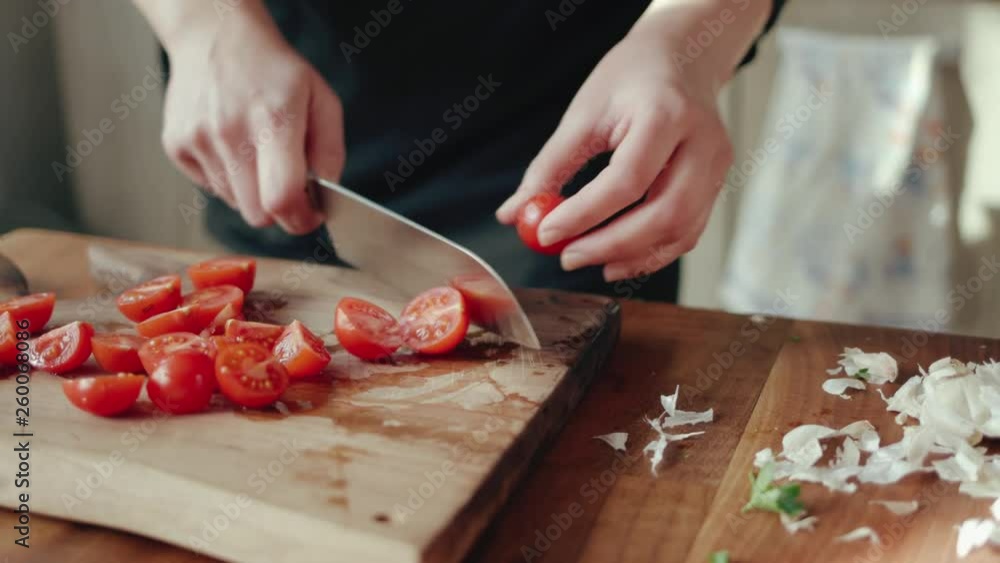 Female chef chopping cherry tomatoes on a wooden board 4k Female chef chopping cherry tomatoes on a wooden board 4k