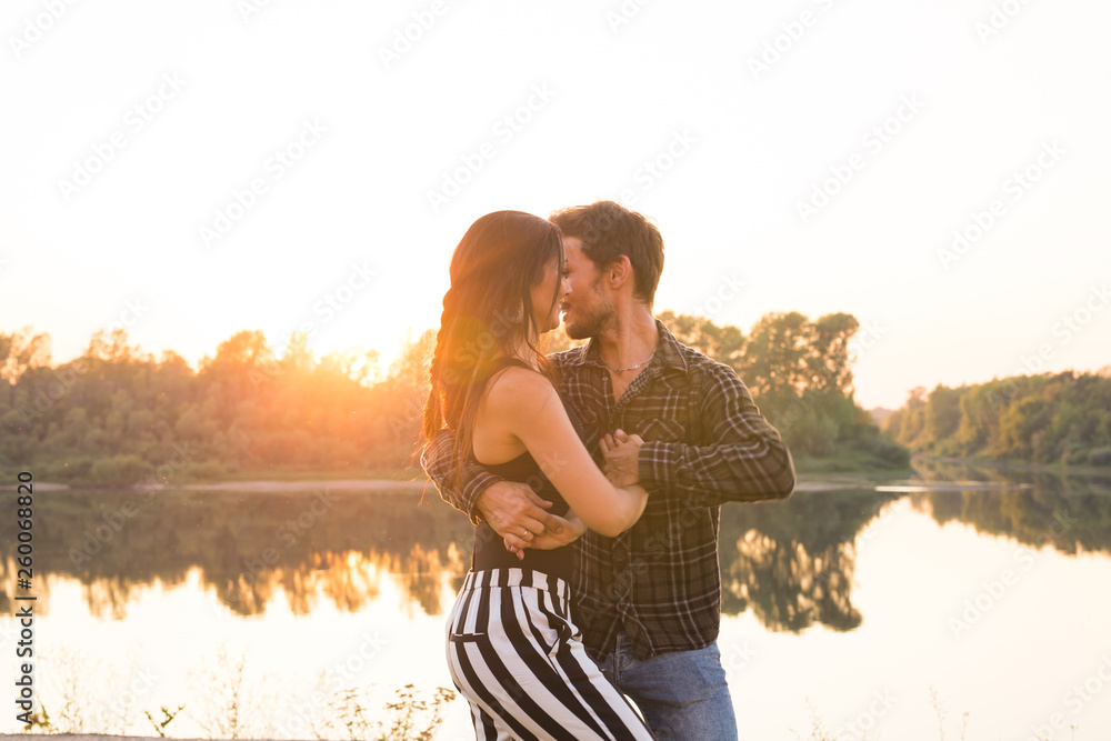 Romantic, social dance and people concept - young couple dancing a tango or bachata near the lake - obrazy, fototapety, plakaty 