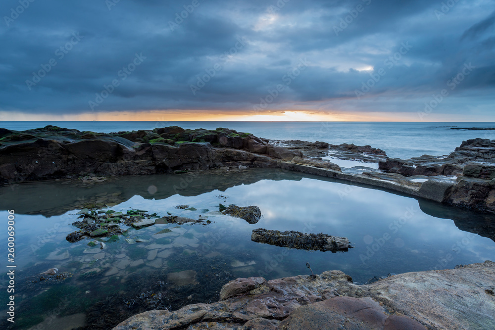 Old and disused bathing pool at Table Rocks, Whitley Bay, on the north east coast of England at sunrise on an overcast day.