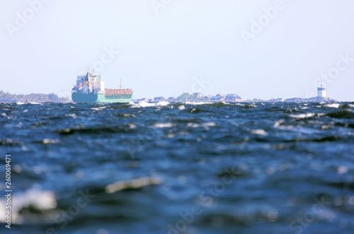 Large carrier ship loaded with timber on the stormy ocean in the swedish archipelago close to the lighthouse Svartklubben