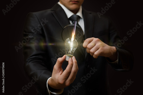 A businessman looking at the idea lightbulb through the magnifier.