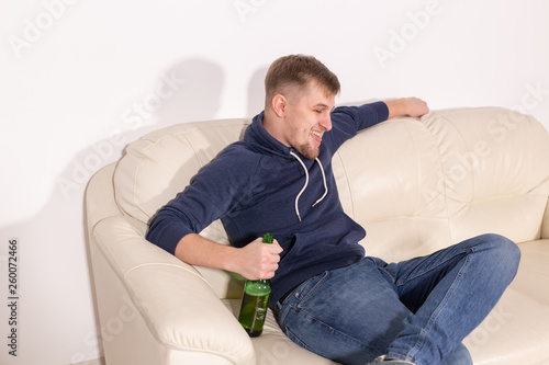 Depression and alcoholism concept - aggressive young man sitting on a sofa with bottle of alcohol © satura_