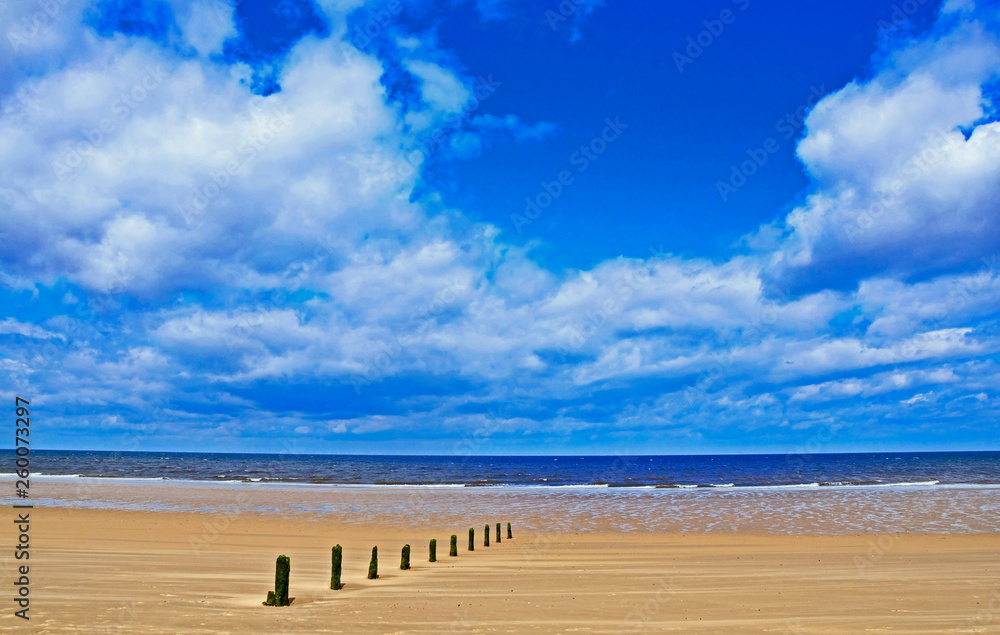 A sunny day with big cumulus clouds and the wide sandy beach at Blakeney in Norfolk England