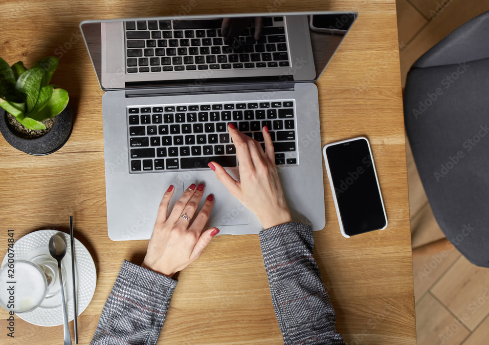 Flat lay. Businesswoman work on laptop for project. Millennial at home office drink coffee looking for job on notebook. Unrecognizable woman using modern portable computer and phone Flat lay. Businesswoman work on laptop for project. Millennial at home office drink coffee looking for job on notebook. Unrecognizable woman using modern portable computer and phone